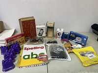 Overview photo of all items including spelling workbook, purple stampers, shape cards, toys and educational items in original packaging.