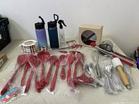 Photo showing the entire kitchen lot with red silicone utensils, ramen bowl, water bottles and other kitchen tools.
