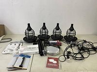 Photo of 4 black metal cage outdoor LED lanterns without posts, string globe lights, and various small accessories including mounting hardware and alarm cards.