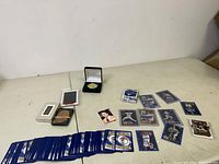 Wide view showing assorted trading cards (Pokémon, baseball, hockey), decks of playing cards, and a collectible coin in a box
