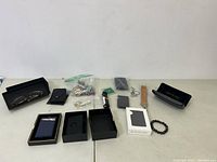 Full lot overview with wallets, keychains, eyeglasses, bracelet, leather strap, and packaging boxes on display