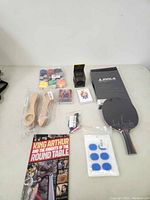 Full view of lot including paddle, comic book, wooden spoons, playing cards, lanyards, adhesive pads, and small fitness-related box
