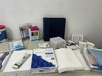 Photo of all stationery items including pads, index cards, labels, and binder on table