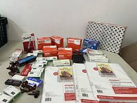 Overview of stationery lot showing multiple boxes of Staples Basics products including rubber bands, paper protectors, and Sharpie markers, along with a calculator and red binder clips