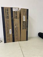 Three unopened boxes of Tip Out Bin storage systems stacked side by side.