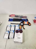 Photo showing blue and black bar clamps with orange and black handles along with packages of Norton abrasive discs and tool hooks.