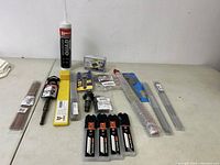 Overview of all tools in lot showing various types including drill bits, utility blades, adhesive tube, abrasive sticks, and multi-tool bits.