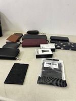 Photo of multiple wallets and wallet accessories arranged on table showing their size, colors, and materials