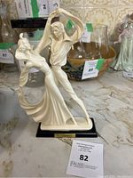 Full view of the 20 inch cream-colored sculpture of a dancing couple on a black base with gold plaque signature of A. Santini.