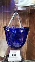 Front angle of dark purple/blue art glass purse with clear handles on display