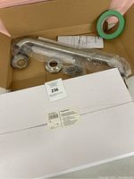 Photo of two new in box chrome faucet handles with installation hardware, instructions, and roll of painter's tape in open box.