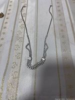 Multi-strand silver chain necklace laid flat on patterned fabric.