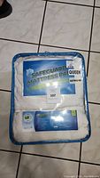 Front view of the packaged mattress pad showing Safeguard branding and queen size label.