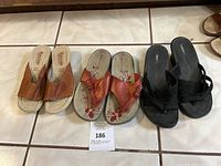 Three pairs of women's sandals displayed side by side on tile floor, including brown wedge sandals, orange thong sandals, and black slip-ons.