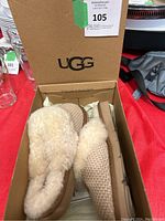 Pair of UGG slippers inside original box showing knit upper and plush shearling lining.