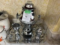 Front view of entire vintage chrome percolator set on tray including percolator, creamer, sugar bowl, and spoon-like tool.