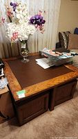 Photo of wood coffee table with brown inset top and floral vase on top, with visible scratches and wear.