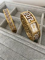 Photo showing gold and silver tone bracelet watch and matching bracelet with Greek key design displayed in jewelry case