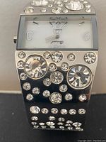 Close-up of the watch face and crystal-adorned bracelet band showing crystal arrangement and rectangular dial with silver hour markers and hands.