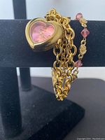 Photo of gold-tone heart-shaped bracelet watch with pink dial and attached chain link bracelet.
