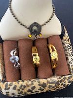 Three rings placed on brown felt ring holder with leopard print base, showing the front and gemstone details.