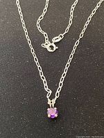 Sterling silver linked chain necklace with a small round purple amethyst pendant and spring ring clasp.