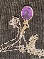 Close-up photo of the sterling silver necklace featuring an oval-shaped faceted amethyst pendant on a delicate silver chain with spring ring clasp.