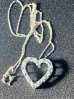 Photo of heart-shaped pendant on a sterling silver chain, showing blue and white topaz stones alternating around the heart shape.