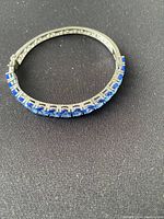 Sterling silver hinged bangle bracelet showing top view with blue stones set along the top half of the bracelet.