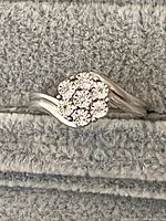 Front angled view of a sterling silver ring showing the floral cluster of clear stones on a twisted band.