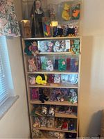 Full view of wooden shelving with multiple Beanie Babies and display cases, plus nun figurine on top shelf.