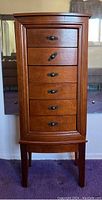 Front view of wooden jewelry floor chest showing six drawers with metal handles and surface wear.