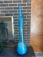 Full front view of tall turquoise glass swung vase showing base swirl and two spouts