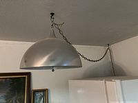 Full view of the mid-century aluminum swag light hanging from ceiling with chain.