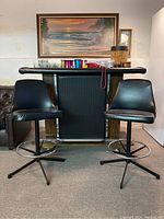 Bar with padded black vinyl top, wood paneling with chrome accents, and two black vinyl bar stools in front