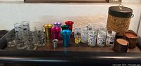 Wide view of the assorted glassware and metal cups alongside the cork ice bucket and wooden coasters.
