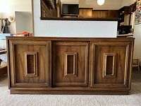 Front view of walnut veneer three-door credenza showing recessed panel doors and plinth base