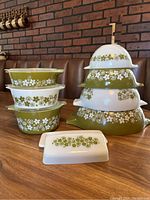 Four stacked Cinderella mixing bowls showing alternating olive-green and white bases with floral band pattern.