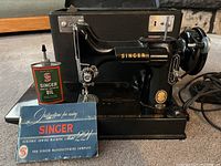 Front view of sewing machine with instruction manual and oil can