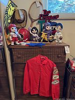 Photo showing various Jeffco Sports ceramic figures, vintage sports memorabilia, and a red jacket on wooden dresser under window
