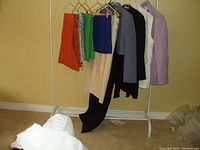 Clothing rack holding colorful ZARA garments including orange pants and jackets of various colors.