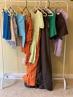 Photo showing entire clothing lot hanging on rack including tops, dresses, shorts, romper, and capris