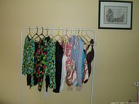 Full view of all 13 bodysuits hung on a white metal rack showing various colors and designs.