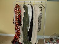 Photo showing 8 pieces of clothing hanging on white metal rack with multi-color geometric print item at the front and others with neutral colors behind