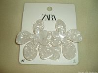 Close-up photo of white floral earrings attached to ZARA branded card.
