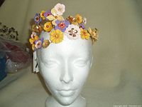 Front view of ZARA metal floral hair band displayed on mannequin head showing layered colorful flowers.