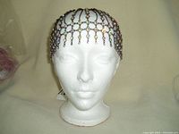 Front view of the metal and crystal headpiece displayed on a white mannequin head showing the full design draped over the head.