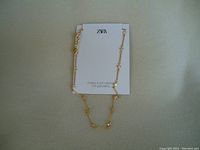 Gold plated necklace with crystal accents displayed on ZARA branded backing card with attached tag.