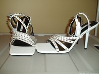 Photo showing the white strappy ankle wrap shoes with silver studs, open toe and slim heel, new with tag.