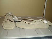 Photo showing a pair of beige suede-like ankle wrap slides by ZARA with attached tags.